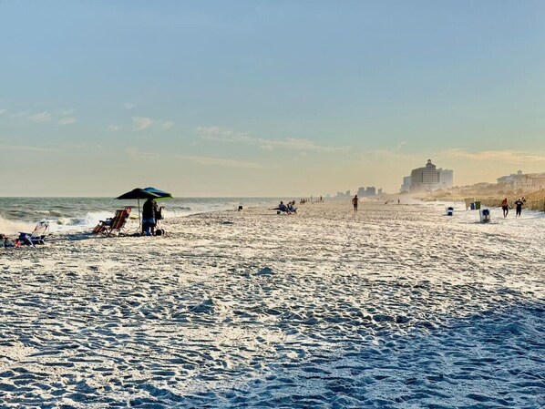 Une plage avec des gens, des chaises et un parasol.