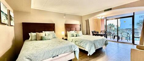 A hotel room with two beds, a balcony with outdoor seating, and a view of the city.