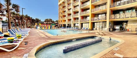 A hotel pool area with lounge chairs and a hot tub.