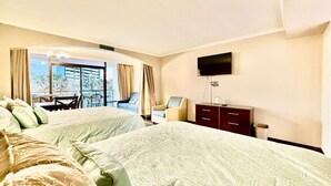 Ein Hotelzimmer mit zwei Betten, einem Fernseher, einem Schreibtisch und Blick ins Freie.