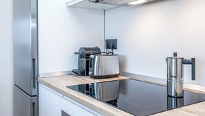 A modern kitchen with a built-in stove, a coffee maker, and a kettle on the countertop.