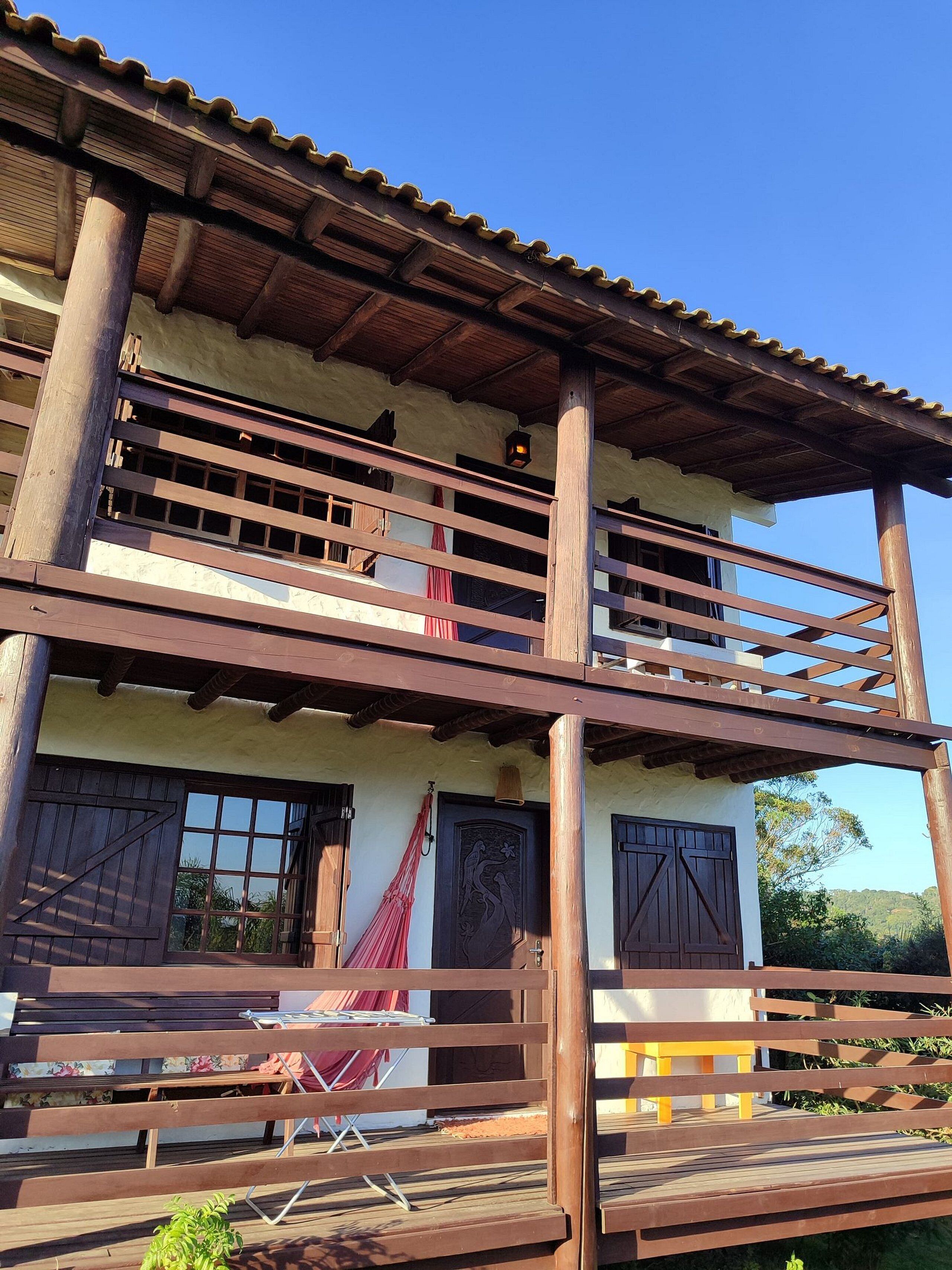 Un edificio de dos pisos con balcón, barandilla de madera y puerta con detalles decorativos.