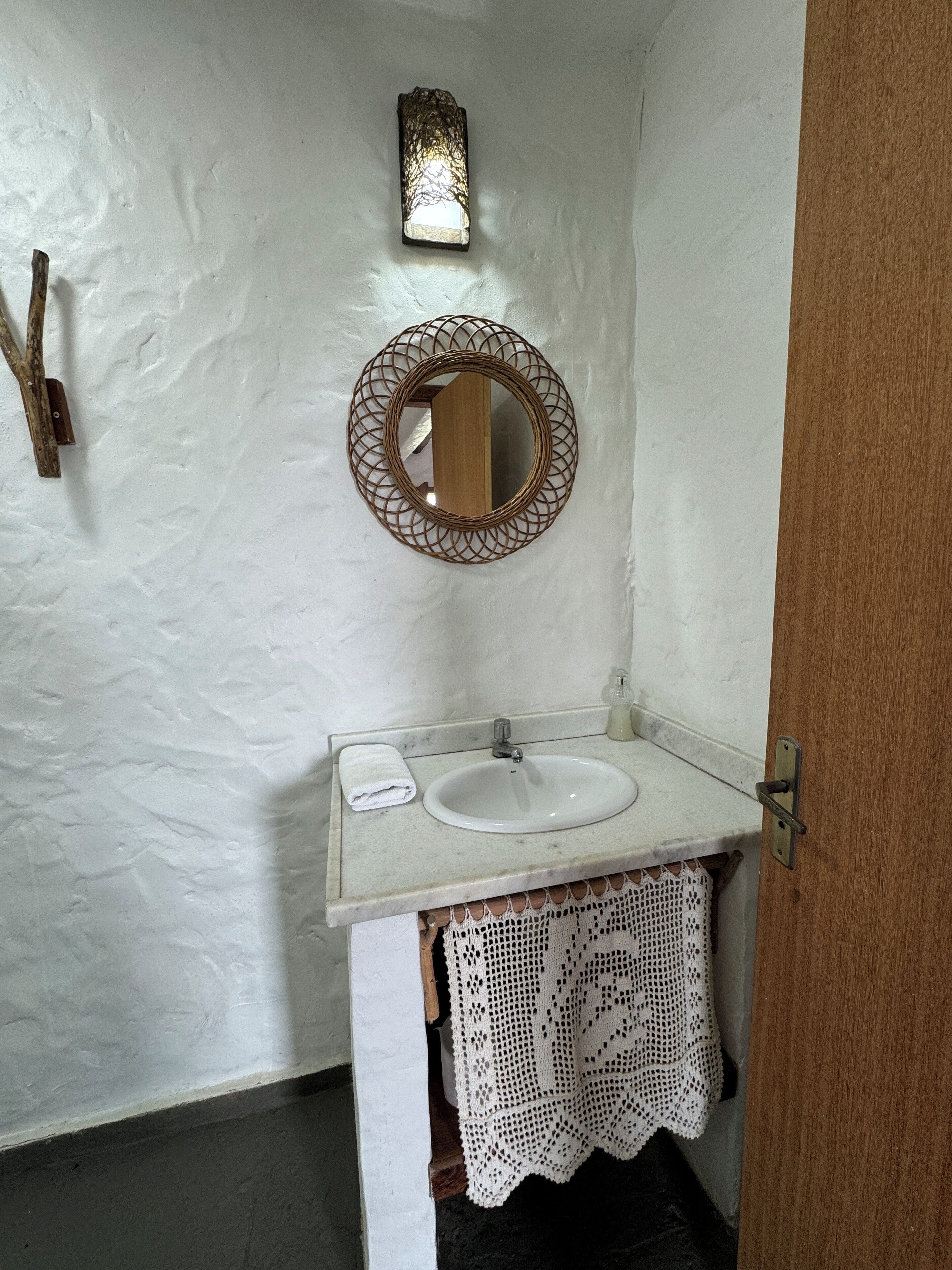 A bathroom with a white sink, a mirror, and a wall-mounted light fixture.