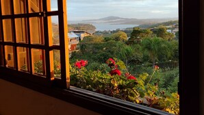 Una stanza con vista su un paesaggio verde e una lontana distesa d'acqua.