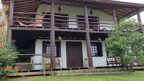Un edificio di due piani con un balcone, una porta in legno e un piccolo giardino.