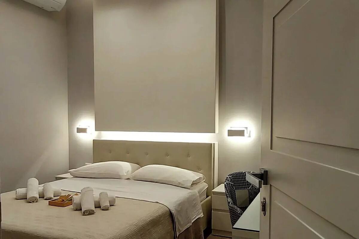 Una habitación de hotel moderna con una cama grande, lámparas de noche y un equipo de aire acondicionado.
