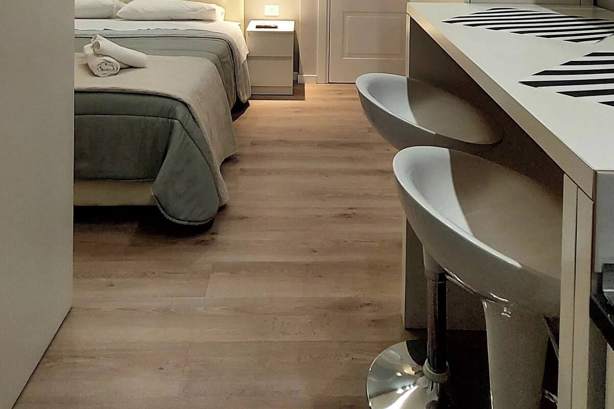 Un dormitorio moderno con cama, mesitas de noche, un espejo y un tocador con lavabo.