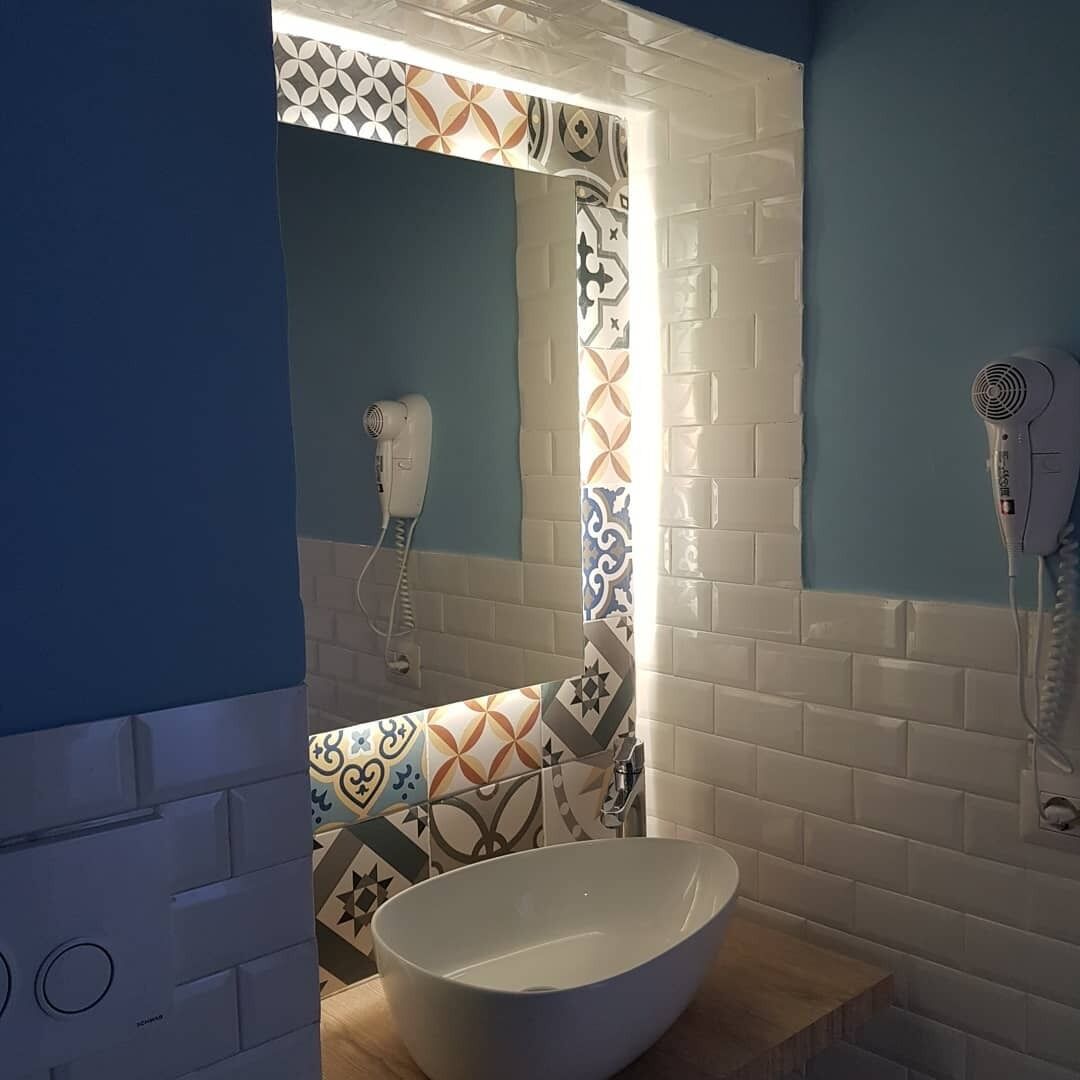 A bathroom with a white sink, a hairdryer, and a mirror.