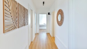 Un couloir orné de décorations murales en bois, avec un miroir tressé, et une vue sur une chambre à coucher avec un lit et une fenêtre.
