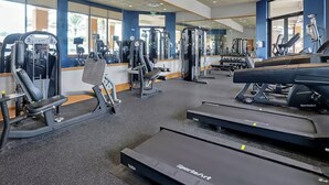 Une salle de sport équipée de divers appareils d’exercice, notamment des tapis de course et des appareils de musculation.