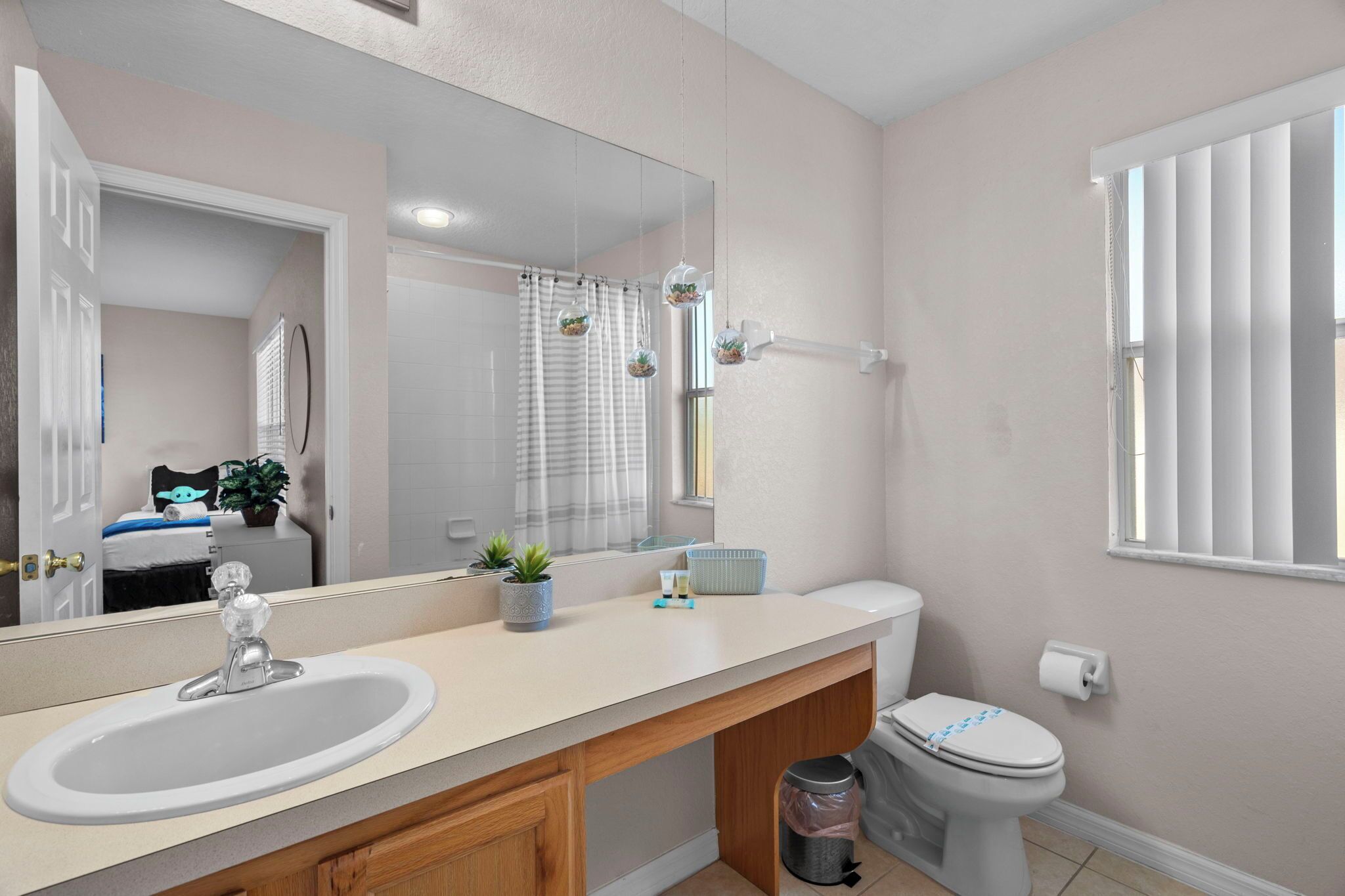A bathroom with a sink, toilet, and a large mirror.