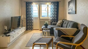 A living room with a sofa, a coffee table, a TV, and a small stool. - 3 bedroom gorgeous home in Ljungby (Ljungby)