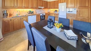 A kitchen with wooden cabinets, a dining table with chairs, and a refrigerator. - 3 bedroom gorgeous home in Ljungby (Ljungby)