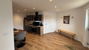 A modern kitchen with wooden cabinets, a dining area with a bench, and a small table.