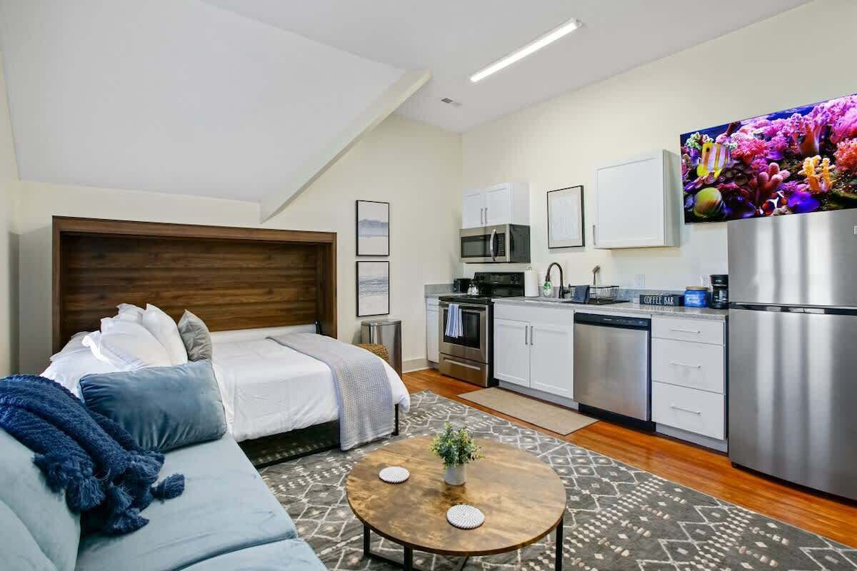 Un apartamento moderno con un dormitorio, kitchenette y sala de estar.