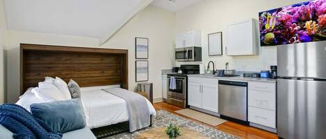 Un apartamento moderno con un dormitorio, kitchenette y sala de estar.