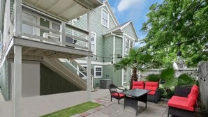A covered patio area with a staircase, outdoor seating, and a small garden.