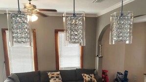 A living room with a sectional sofa, round chairs, and hanging crystal chandeliers.