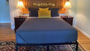 Un letto rifatto con copriletto trapuntato, due lampade da comodino e una testiera decorativa.