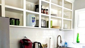 Una cucina moderna con mobili bianchi, un frigorifero in acciaio inossidabile, una macchina da caffè e un lavello.