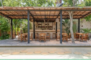 Relax in a serene outdoor space surrounded by lush greenery and shaded by a pergola.