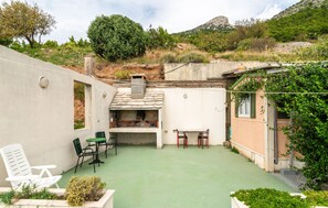 Un patio con zona de barbacoa, mobiliario exterior y vistas del paisaje circundante.