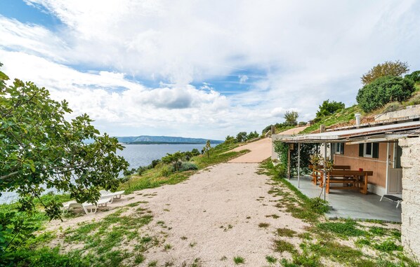 Una propiedad costera con un sendero de arena que lleva a una casa con terraza.