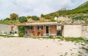 Una pequeña casa de una sola planta con un patio, una mesa y sillas.