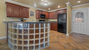 A kitchen with wooden cabinets, a black refrigerator, and a glass block island. - Condo at Sunbay Resort! Heated Pool & Hot Tub! (Hot Springs)