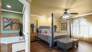 A bedroom with a four-poster bed, a sitting area with a bench, a bathtub, and a ceiling fan. - Condo at Sunbay Resort! Heated Pool & Hot Tub! (Hot Springs)