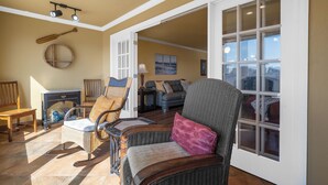 A living room with wicker furniture, a wooden rocking chair, and a large window. - Condo at Sunbay Resort! Heated Pool & Hot Tub! (Hot Springs)