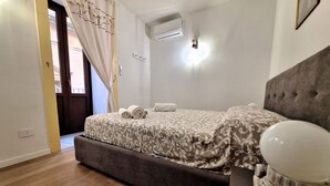 Un dormitorio con cama, unidad de aire acondicionado, puerta y cortina.