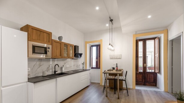 Una cocina moderna con armarios blancos, encimera de mármol y detalles de madera.