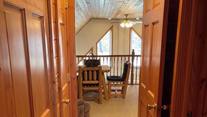 A wooden interior with a staircase leading to a balcony. - Adirondack Red House, Adirondack Red House (Eagle Bay)