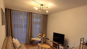 En stue med sofa, sofabord, tv og spiseplads med stole.