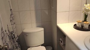 Et lille badeværelse med toilet, vask og spejl.