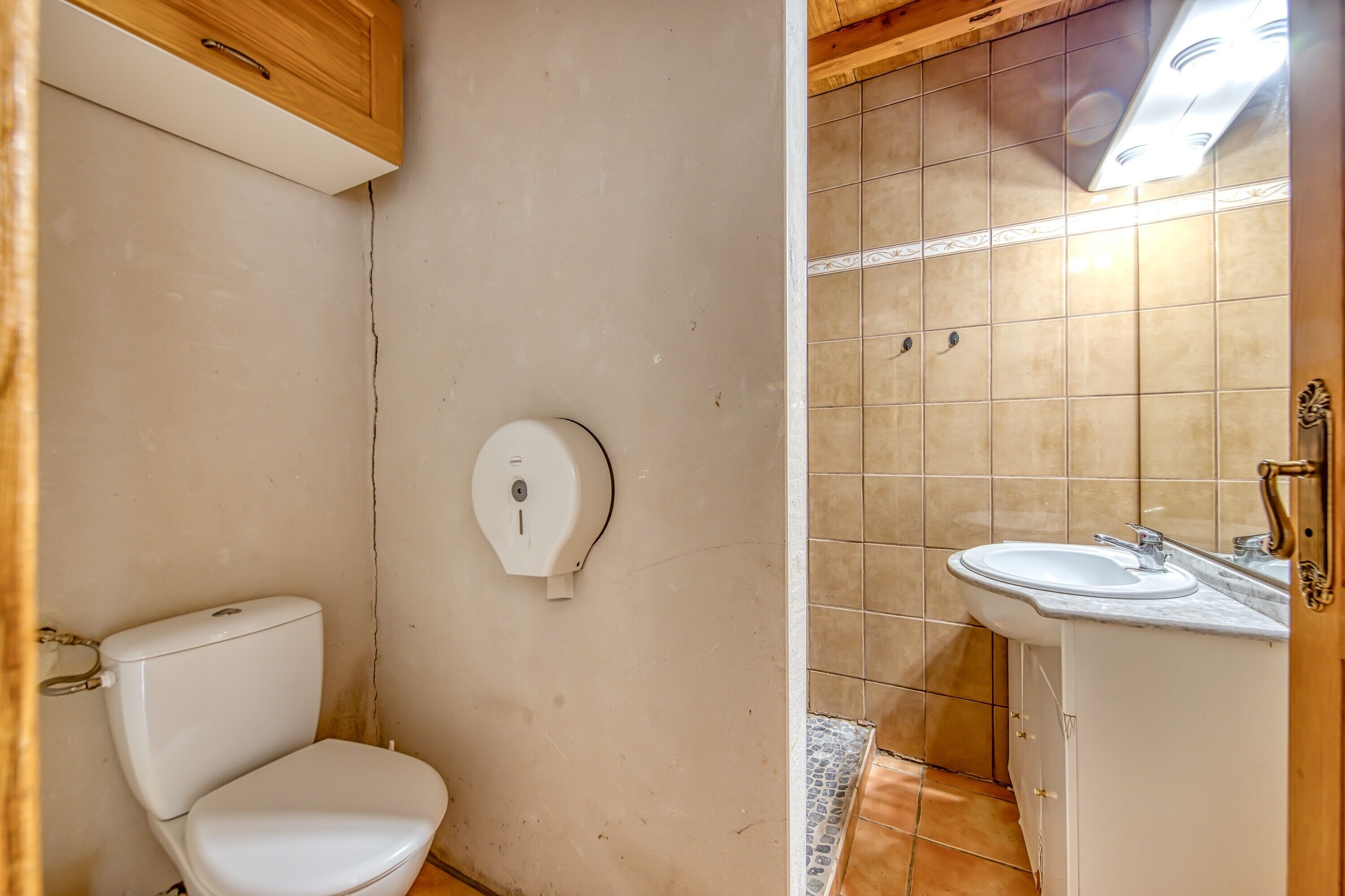A bathroom with a toilet, a hand dryer, and a sink with a mirror.