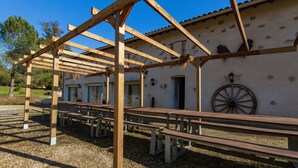 A building with a pergola structure, outdoor seating, and a wheelbarrow on the wall. - Holiday Home 'La Grange' with Private Pool, Private Terrace and Wi-Fi (Guizengeard)
