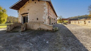 A building with a sloped roof, a front entrance, and a gravel driveway. - Holiday Home 'La Grange' with Private Pool, Private Terrace and Wi-Fi (Guizengeard)
