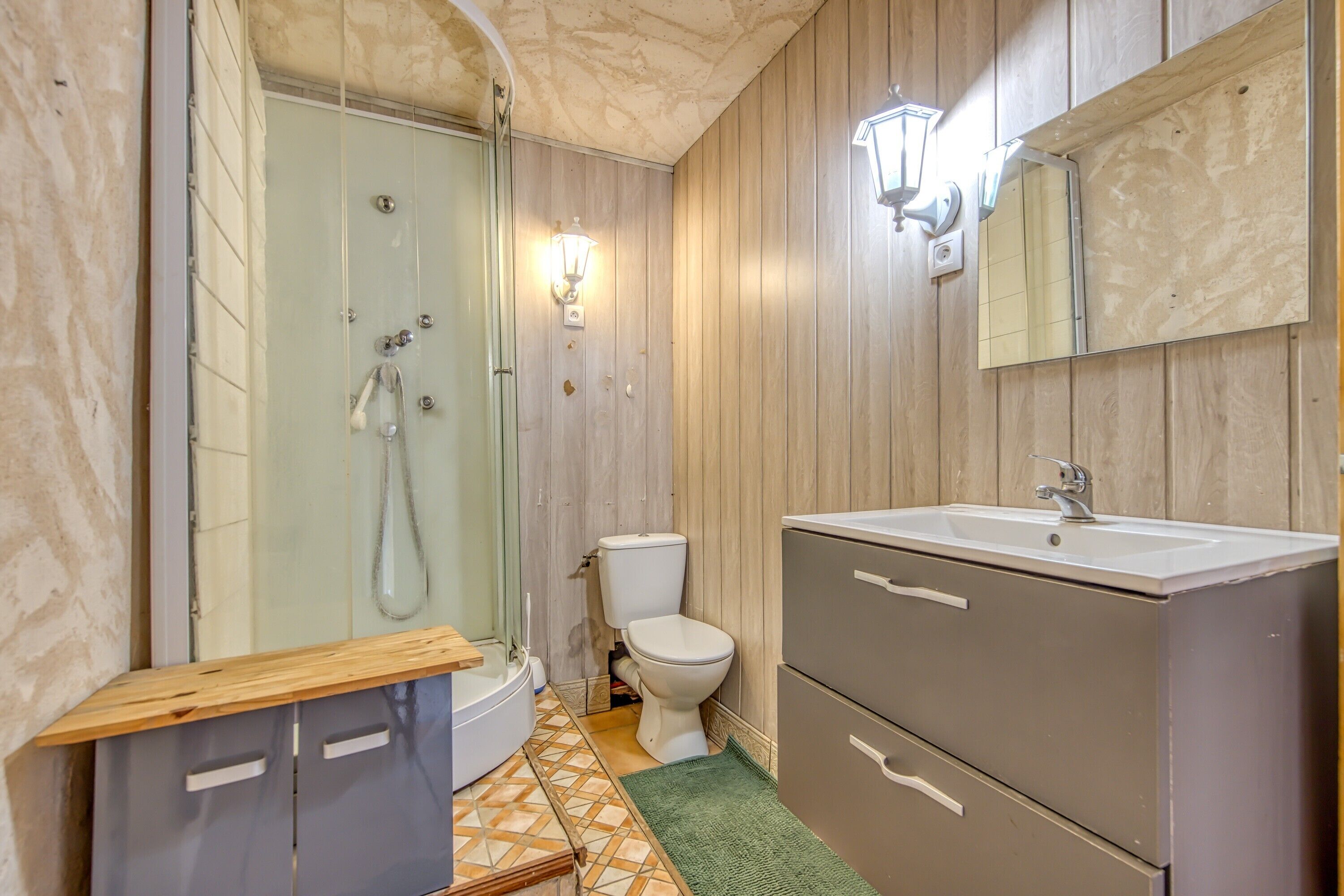 A bathroom with a shower, toilet, sink, and cabinets.