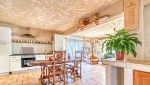 A kitchen with a dining table, chairs, a stove, and a refrigerator. - Holiday Home 'L'Ecurie' with Private Pool, Private Terrace and Wi-Fi (Guizengeard)
