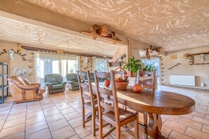 A spacious living area with a wooden dining table, chairs, a sofa, and a fireplace.
