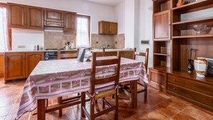 Una cocina con armarios de madera, una mesa de comedor con mantel floreado y un aparador con adornos.