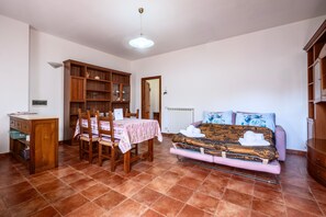 A room with a dining table, chairs, a sofa, and a cabinet. - Apartment 'Casa Doriana' with Balcony and Wi-Fi (Poggio Murella)