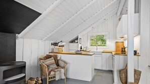 Une cuisine chaleureuse avec un plafond en bois, une cuisinière encastrée et une chaise rustique.