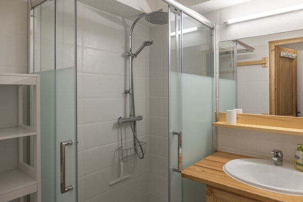 A bathroom with a glass-enclosed shower, a wooden vanity with a sink, and a mirror above the vanity.