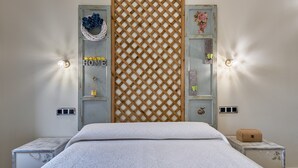 A bedroom with a bed, two nightstands, a wooden lattice partition, and wall-mounted sconces.
