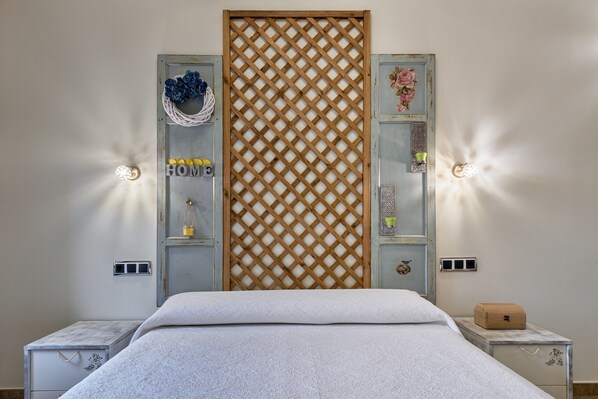 A bedroom with a bed, two nightstands, a wooden lattice partition, and wall-mounted sconces.