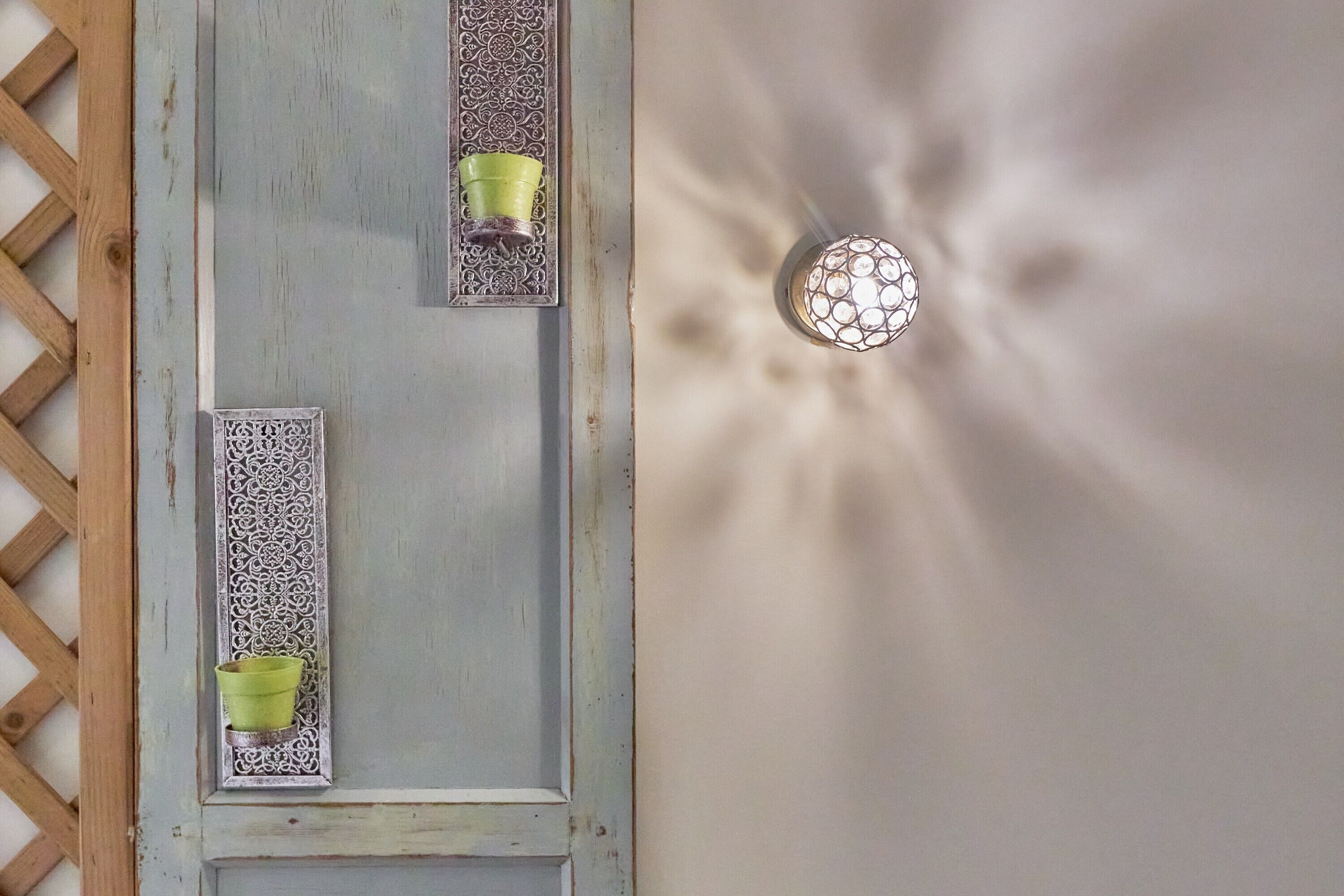 Una puerta con paneles decorativos y dos candelabros verdes.