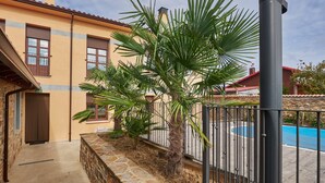 A building with a stone wall, a palm tree, and a pool.
